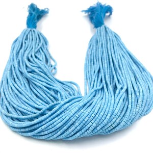 Könnte beinhalten: Eine Strähne aus hellblauen Türkisperlen. Die Perlen sind klein und rund und auf einem dünnen Faden aufgereiht. Die Perlen sind in einem lockeren, fließenden Muster angeordnet.