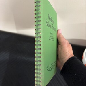 May include: A green spiral bound book titled "Walleigh's Salad Book". The book has a white spine with the text "The L. B. Walleigh Company, Veour - Home - Products - Prices - Dealers - Distributors - Wholesale - Retail - Eastern Shore, Md."