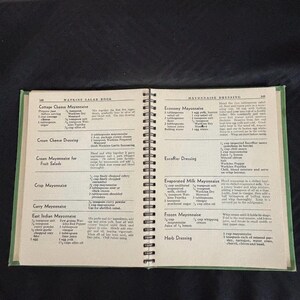 May include: A vintage Watkins Salad Book with recipes for mayonnaise, salad dressings, and other condiments. The book has a green cover and is open to pages with recipes for mayonnaise, including Economy Mayonnaise, Escoffier Dressing, Evaporated Milk Mayonnaise, Frozen Mayonnaise, and Herb Dressing.