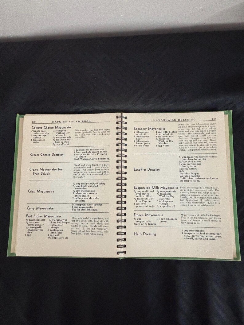 May include: A vintage Watkins Salad Book with recipes for mayonnaise, salad dressings, and other condiments. The book has a green cover and is open to pages with recipes for mayonnaise, including Economy Mayonnaise, Escoffier Dressing, Evaporated Milk Mayonnaise, Frozen Mayonnaise, and Herb Dressing.