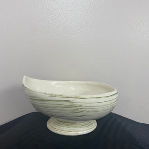 May include: A white ceramic bowl with a green and white striped design. The bowl is on a pedestal base.