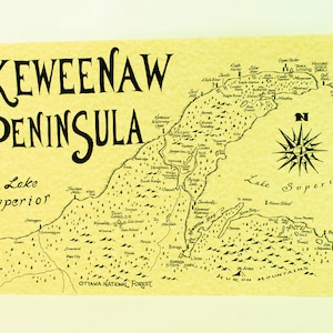 May include: A vintage-style map of the Keweenaw Peninsula in Michigan, featuring the text "KEWEENAW PENINSULA" in a large, decorative font. The map shows the peninsula's geography, including rivers, lakes, and towns, with a compass rose in the upper right corner. The map is printed on a light yellow background with a textured paper effect.