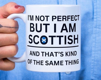 May include: White ceramic mug with black text that reads "I'm not perfect but I am Scottish" with a blue and white Scottish flag symbol. The text continues "and that's kind of the same thing".
