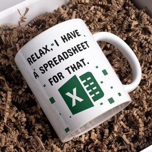 May include: White coffee mug with a green and black Microsoft Excel logo and the text "Relax, I have a spreadsheet for that."