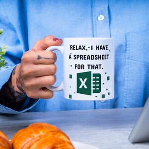 Puede incluir: Taza de caf&eacute; blanca con el texto "Relax, I have a spreadsheet for that." y un logotipo de Excel verde.