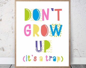 May include: A colorful print with the text "DON'T GROW UP (it's a trap)" in a retro style. The letters are in different colors and have a variety of patterns.