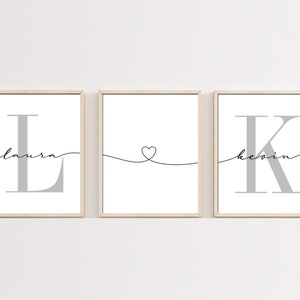 May include: Three framed prints featuring the letters L and K in grey, with the names Laura and Kevin written in cursive beneath each letter. The centre print has a heart shape drawn with a line.