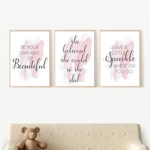 May include: Three framed prints with pink watercolour backgrounds and inspirational quotes. The first print says "Be your own kind of beautiful". The second print says "She believed she could so she did". The third print says "Leave a little sparkle wherever you go".