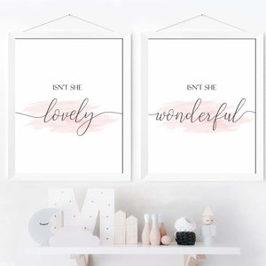 May include: Two white framed prints with pink watercolor accents. The left print says "Isn't she lovely" and the right print says "Isn't she wonderful".