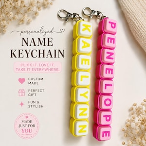 May include: Two vertical keychains with silver-tone lobster clasps. One keychain features yellow square beads spelling KAELYNN, and the other features pink square beads spelling PENNELOPE. Text on the image reads: personalized NAME KEYCHAIN.