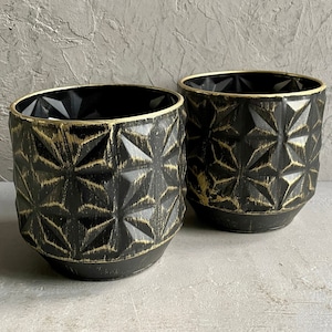 May include: Two black and gold geometric patterned planters. The planters have a distressed look with a gold metallic finish.