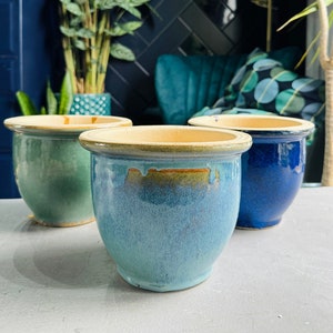 May include: Three ceramic plant pots in different shades of blue and green. The pots are glazed and have a rustic, handmade look.