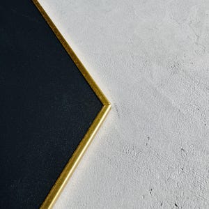 May include: A black chalkboard with a gold frame. The frame is a simple, rectangular shape.