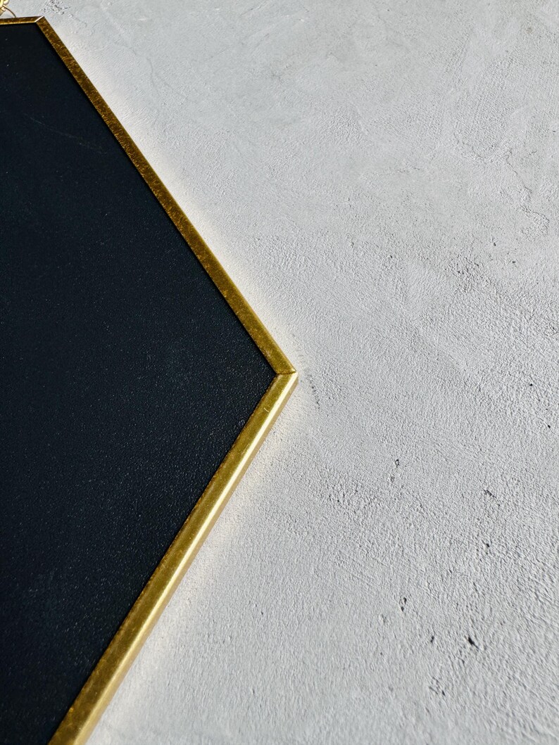 May include: A black chalkboard with a gold frame. The frame is a simple, rectangular shape.