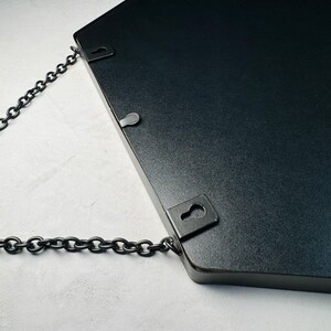 May include: Black hexagonal mirror with a chain hanging from two metal hooks on the back.