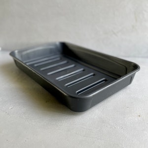 May include: A black plastic rectangular tray with drainage holes. The tray is designed for use with plant pots.