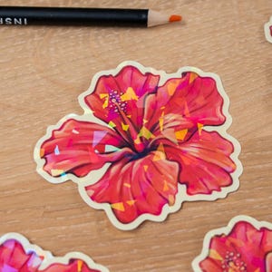 May include: Several red hibiscus flower stickers with a holographic effect are arranged on a wooden surface. A black pencil with the text "INSPIRE YOURSELF" is also present. The stickers have a white border.