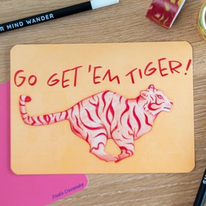 May include: A motivational card with a pink tiger illustration and the text "Go get 'em tiger!" in red lettering.