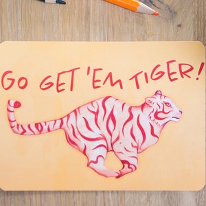 Kaart met de tekst Go Get 'Em Tiger! op een houten oppervlakte.