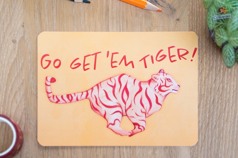 Kaart met de tekst Go Get 'Em Tiger! op een houten oppervlakte.