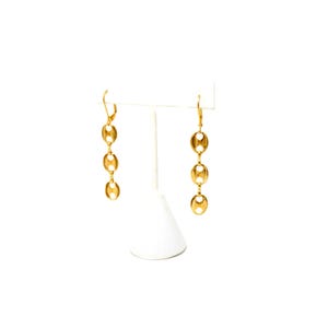 Op de afbeelding: Goudkleurige oorhangers met een ketting van drie ovaalvormige schakels. De oorbellen hebben een klapsluiting en worden gepresenteerd op een witte standaard tegen een witte achtergrond. Een klassiek sieradenontwerp.