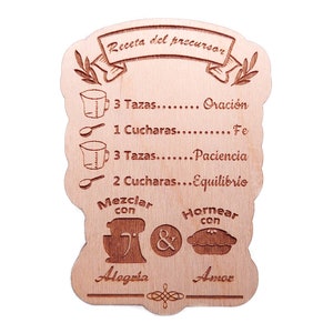Puede incluir: Un letrero de madera con una receta para "precursor" escrita en español. La receta incluye ingredientes como "oración", "fe", "paciencia" y "equilibrio". El letrero también incluye ilustraciones de una batidora, un pastel y las palabras "Alegria" y "Amor".