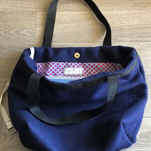Große Tasche aus gekochter Wolle, marineblau, mit bedrucktem Innenfutter mit kleinen bordeauxroten Punkten auf hellblauem Grund.
