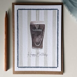 May include: A greeting card featuring a watercolor illustration of a pint of Guinness stout. The card has a striped background and a scalloped border. The words "Happy Birthday" are written below the pint.