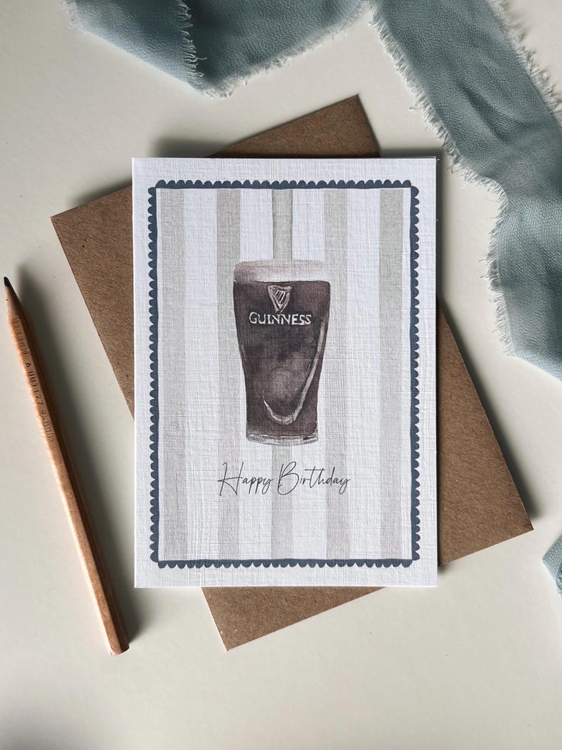 May include: A birthday card featuring a watercolor illustration of a pint of Guinness stout. The card has a striped background and a scalloped border. The words "Happy Birthday" are written below the pint.