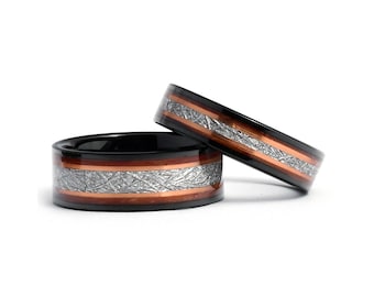 May include: Two black tungsten carbide rings with a copper and meteorite inlay. The rings are stacked on top of each other.