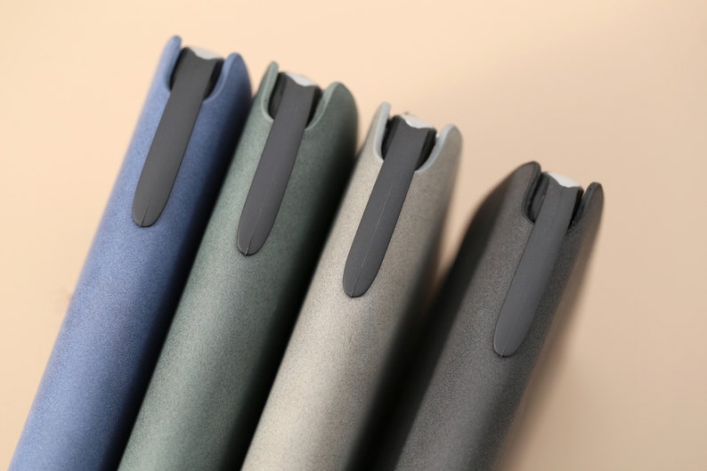 May include: Four slim, rectangular cases in blue, green, gray, and black with a black elastic band closure.
