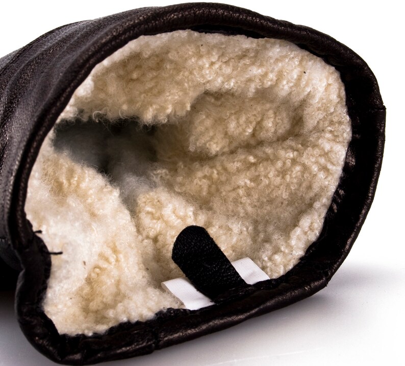May include: Brown leather mitten with a soft, white fleece lining. The mitten has a black strap.