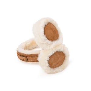 May include: Brown faux fur earmuffs with a brown suede exterior and a white faux fur lining. The earmuffs have a brown leather strap with a buckle.