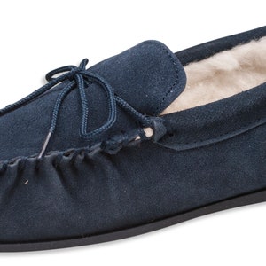 Pu&ograve; includere: Ciabatte mocassino in pelle scamosciata blu navy con fodera in montone e un laccio decorativo.