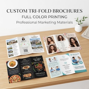 May include: Several custom tri-fold brochures are displayed on a wooden surface. The brochures showcase full-color printing and professional marketing materials. The brochures feature various designs, including real estate, salon services, and restaurant menus.