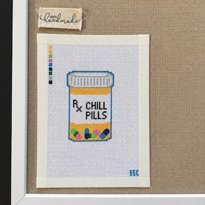 May include: A needlepoint canvas featuring a yellow prescription bottle with a blue cap and the text Rx CHILL PILLS. The design includes a color palette guide on the left, small colorful pill illustrations at the bottom, and the initials SSC in blue.