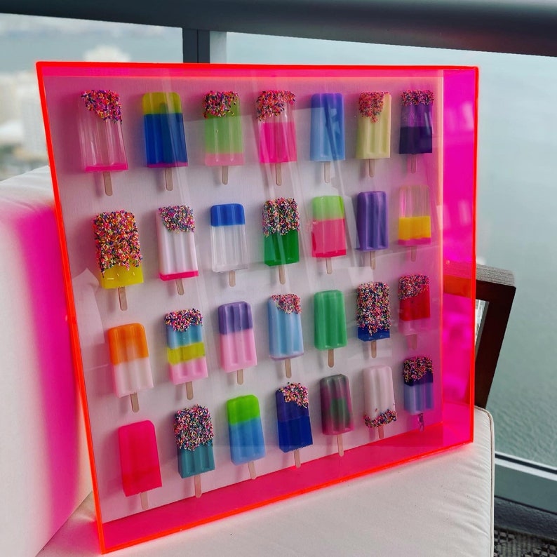 Puede incluir: Una pieza de arte de pared enmarcada de color rosa ne&oacute;n con 36 piezas de resina de forma de paleta de colores con chispas. Las paletas est&aacute;n dispuestas en una cuadr&iacute;cula y todas son de diferentes colores y dise&ntilde;os.