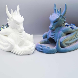 May include: Two dragon-shaped dice trays, one white and one blue, with a compartment for dice. The blue dragon has iridescent paint.