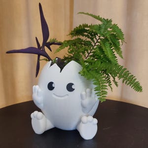 Puede incluir: Una taza de cerámica blanca con un asa negra y el texto "But First, Coffee" en negro y negrita. La taza está sobre una superficie blanca.