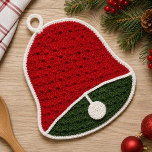 Puede incluir: Un agarrador de crochet en forma de campana con una sección superior roja y una sección inferior verde oscuro, bordeado con hilo blanco. El diseño incluye un pequeño acento circular blanco en la parte inferior y un lazo blanco para colgar.