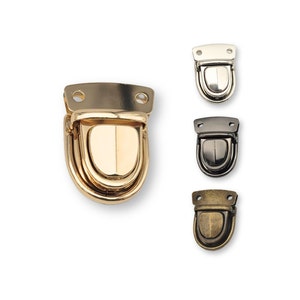 May include: Four different finishes of a metal clasp for a bag or purse. The clasps are in gold, silver, black, and antique brass.