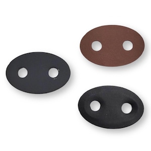 Puede incluir: Tres piezas de cuero ovaladas con dos agujeros cada una. Una es marrón, otra es negra y otra es gris oscuro.