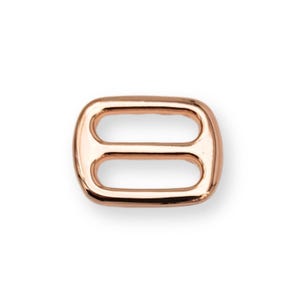 Peut inclure: Boucle en métal or rose de forme rectangulaire avec deux ouvertures ovales. La boucle a des bords arrondis et une surface polie. Ce matériel est adapté à divers projets d'artisanat et de couture. Dimensions : environ 2,5 cm x 1,5 cm.