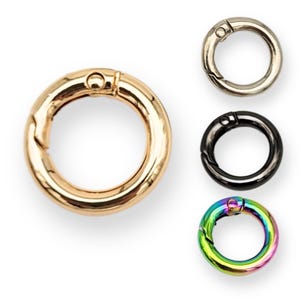 Puede incluir: Cuatro llaveros de metal de diferentes colores. Los llaveros son redondos y tienen un cierre de resorte. Los colores son dorado, plateado, negro y arcoíris.