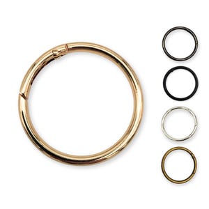 May include: A set of four gold, silver, black, and bronze key rings. Each ring is a simple circle with a spring-loaded clasp.