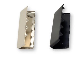 May include: Two metal strap ends, one silver and one black. The ends have a serrated edge and are designed to be used with a strap or ribbon.