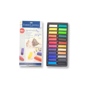May include: A set of 24 mini soft pastels in a black plastic case. The pastels are arranged in rows of four, with each row containing a different colour. The colours include yellow, orange, red, pink, purple, blue, green, and brown. The case has a clear plastic lid that allows you to see the pastels inside. The case also has a label that says "Faber-Castell" and "24 Soft Pastels".