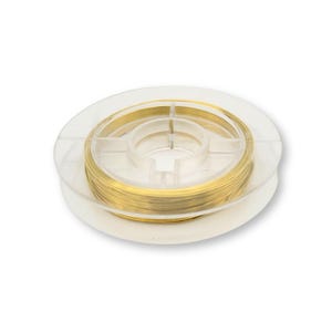 Peut inclure: Une bobine de fil de couleur dorée dans un récipient en plastique transparent. Le fil est enroulé autour d'une bobine centrale.