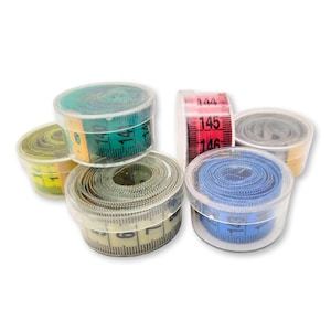 Può includere: Sei contenitori di plastica trasparente con nastri di misura retrattili all'interno. I nastri sono di vari colori, tra cui giallo, verde, blu e rosso. I numeri 144, 145 e 146 sono visibili sul nastro rosso.