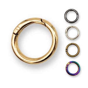 May include: A set of 5 gold-toned metal key rings with a spring-loaded clasp. The key rings are shown in different colours: gold, silver, black, bronze, and rainbow.